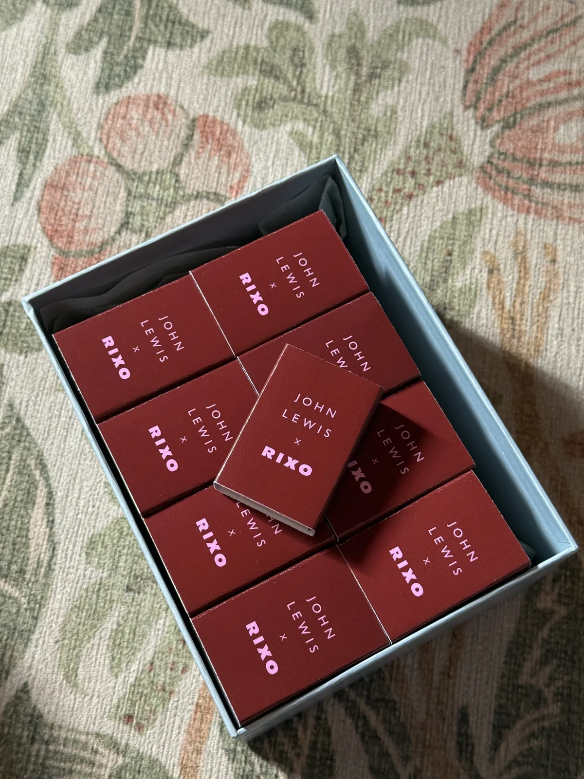 The box of John Lewis × RIXO matchboxes seen from above in low sunlight
