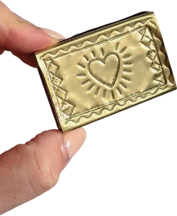 A gold foil matchbox embossed with a heart, held between two fingers