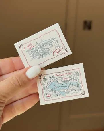 Illustrated matchboxes of a house, held in the hand