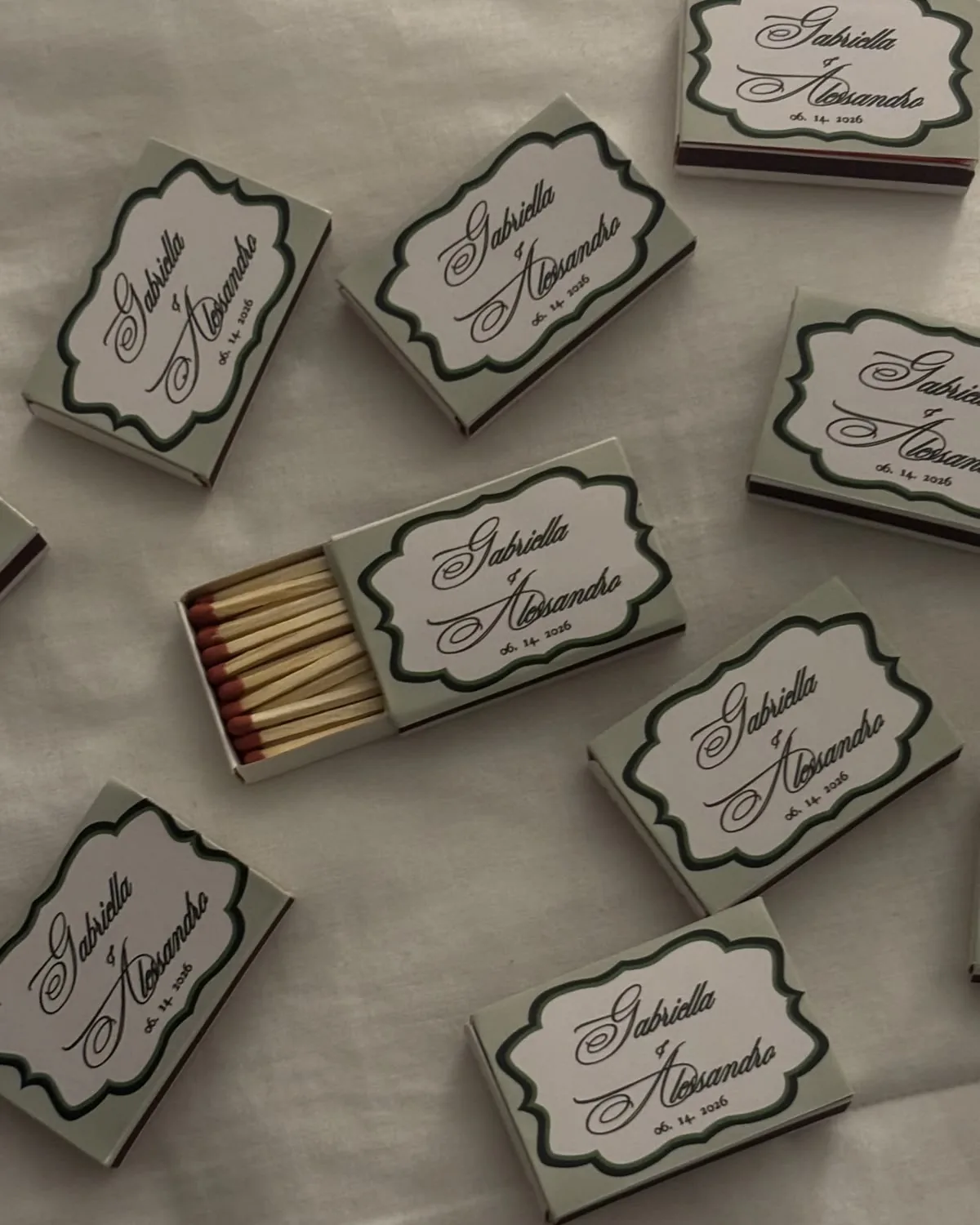 Matchboxes with names in script inside a green scalloped frame