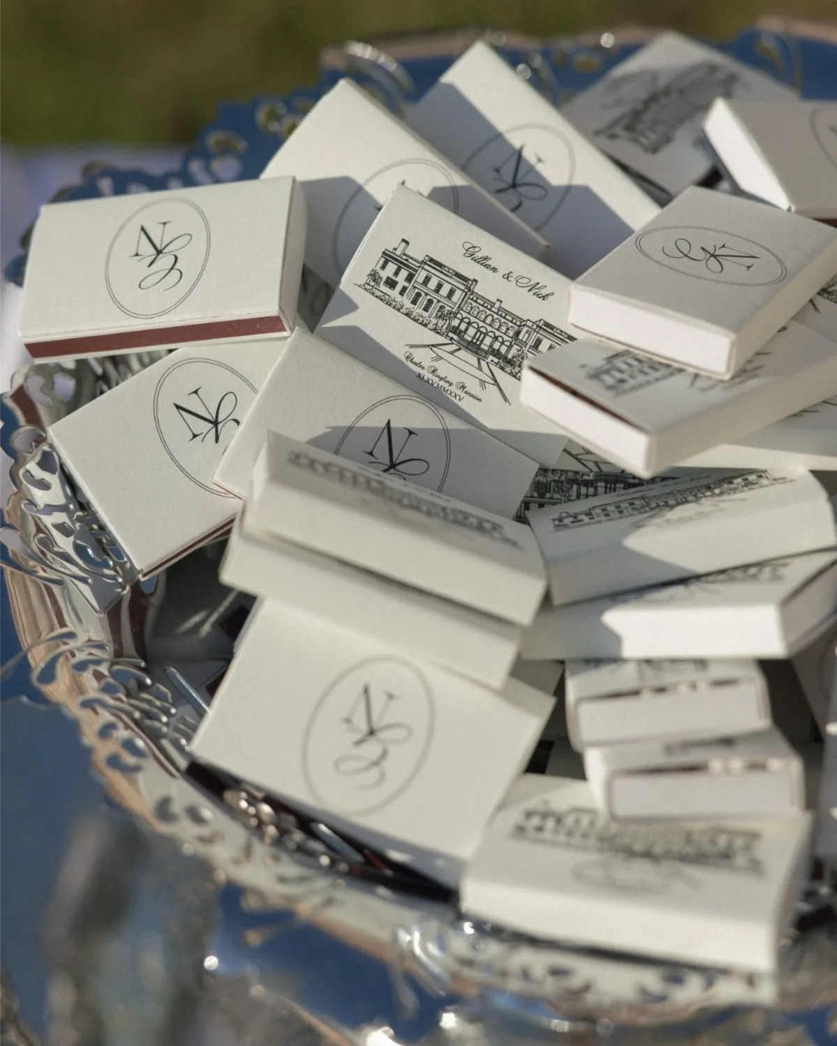 White matchboxes with a monogram and a venue drawing on a silver tray