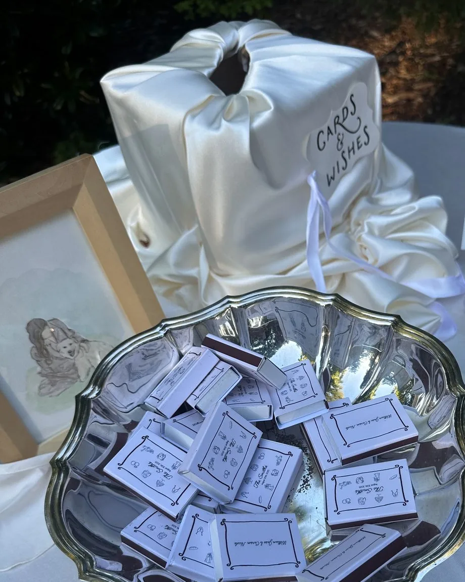 A silver bowl of matchboxes beside a satin cards and wishes box