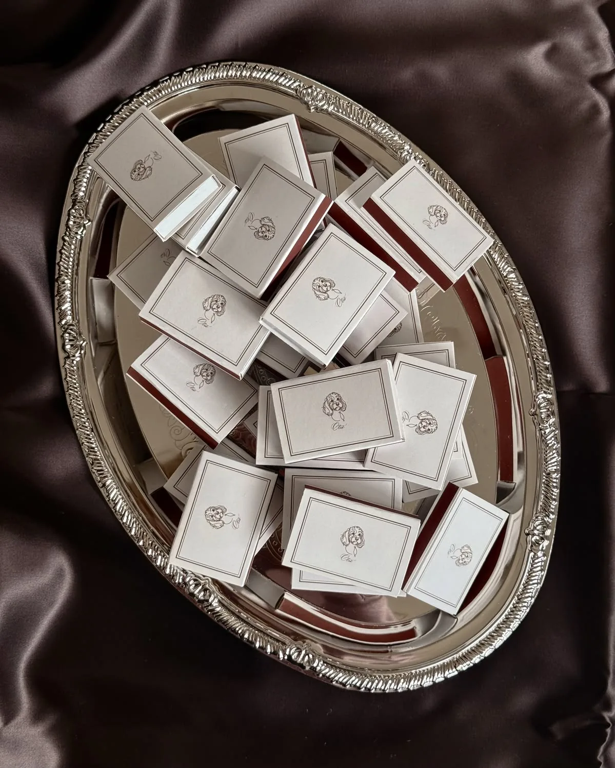 Matchboxes with a small drawn portrait on an oval silver tray over brown satin