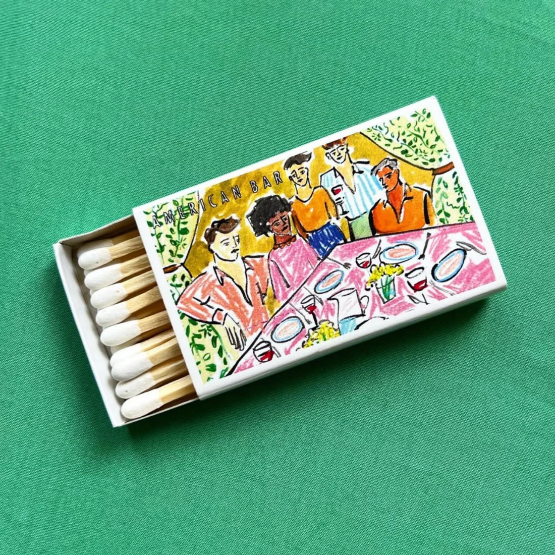 A matchbox illustrated with a bar scene, open on green cloth
