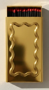 A gold metal matchbox with a wavy frame pressed into the lid