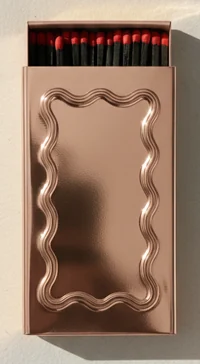 A rose metal matchbox with a wavy frame pressed into the lid