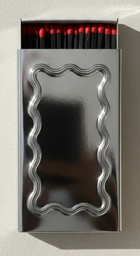 A silver metal matchbox with a wavy frame pressed into the lid