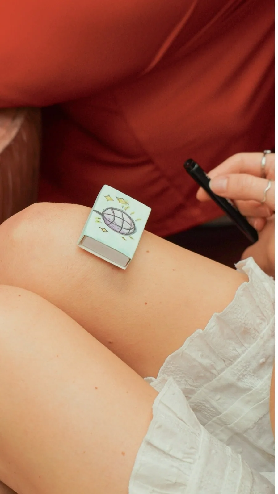 A guest at an event holding the matchbox just drawn for her