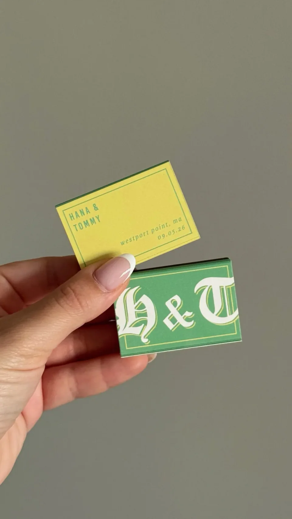 A green matchbox with white gothic initials and a yellow one with names, a place and a date, held in the hand