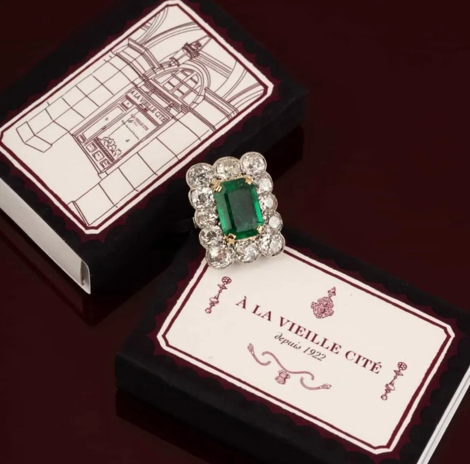 Architectural matchbox design for À La Vieille Cité beside an emerald ring