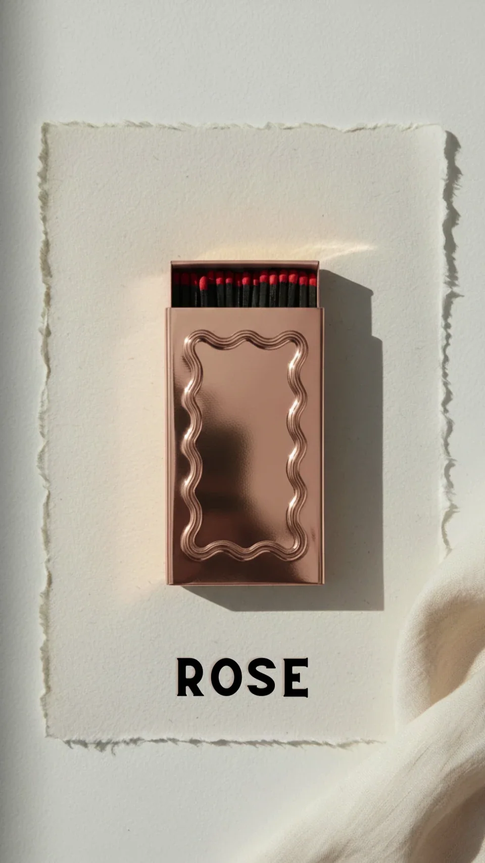 A rose gold metal matchbox with a wavy edge