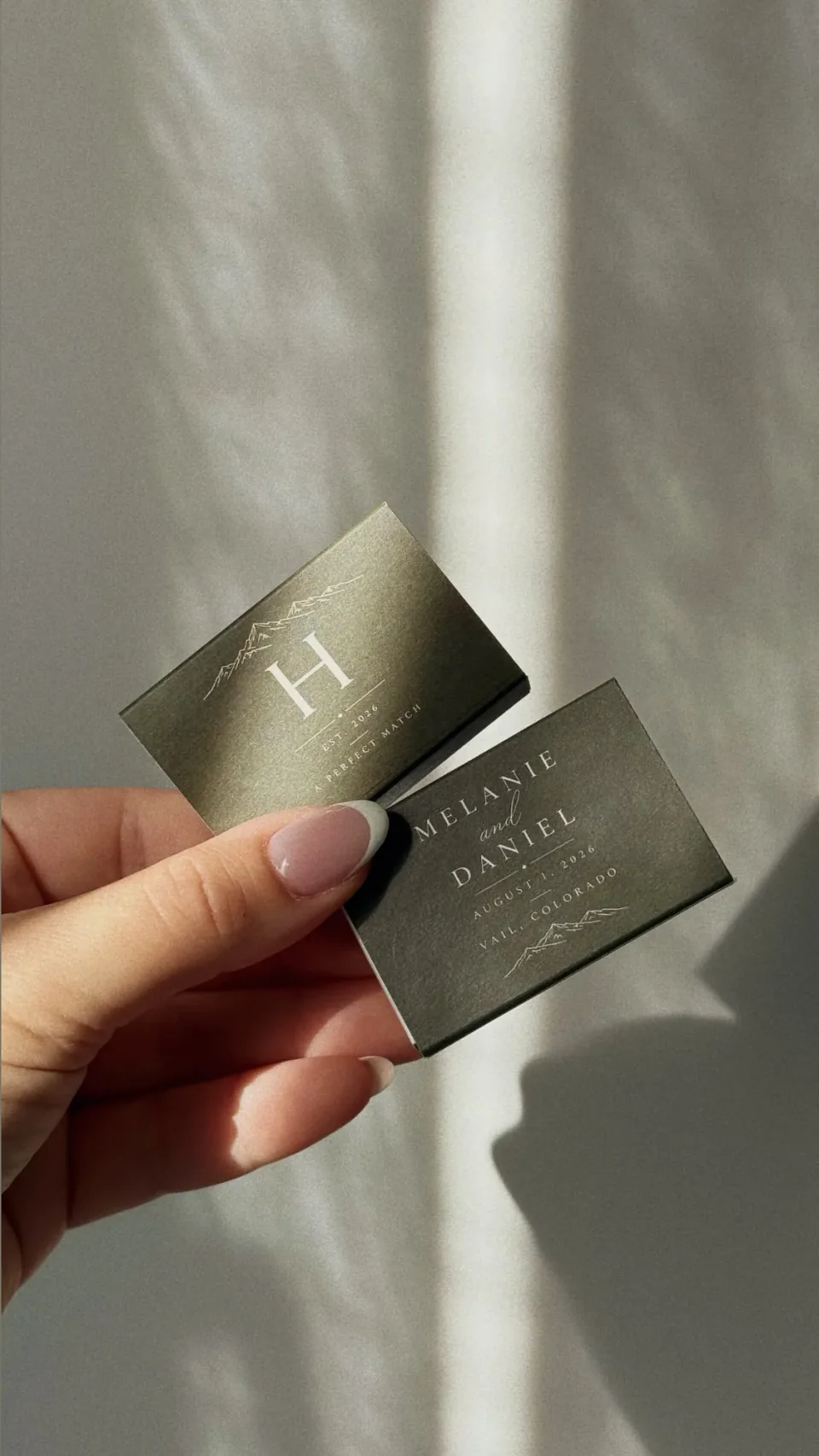 Olive green matchboxes with a white monogram, names, a date and a mountain line