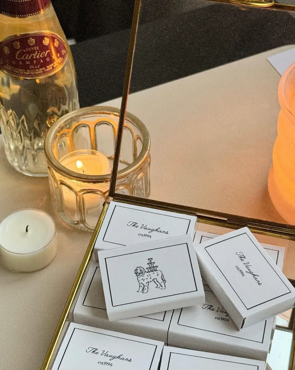 Personalised wedding matchboxes displayed in a mirrored box by candlelight