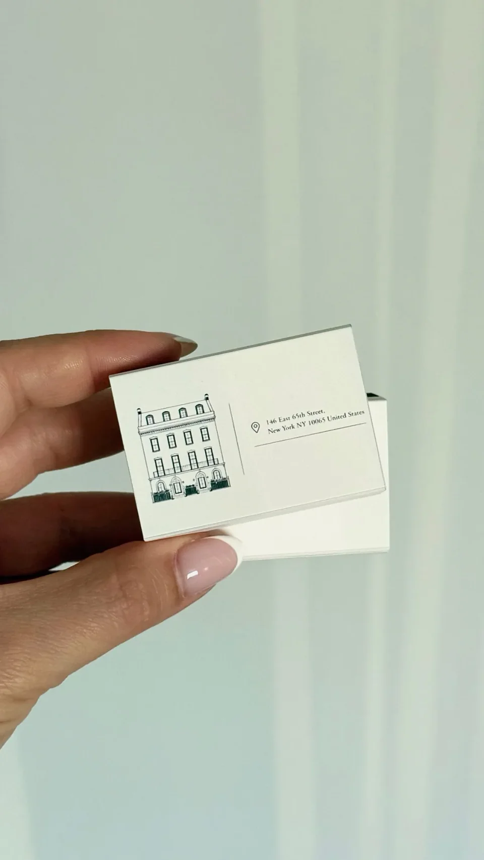 White matchboxes with a fine line drawing of a townhouse beside an address
