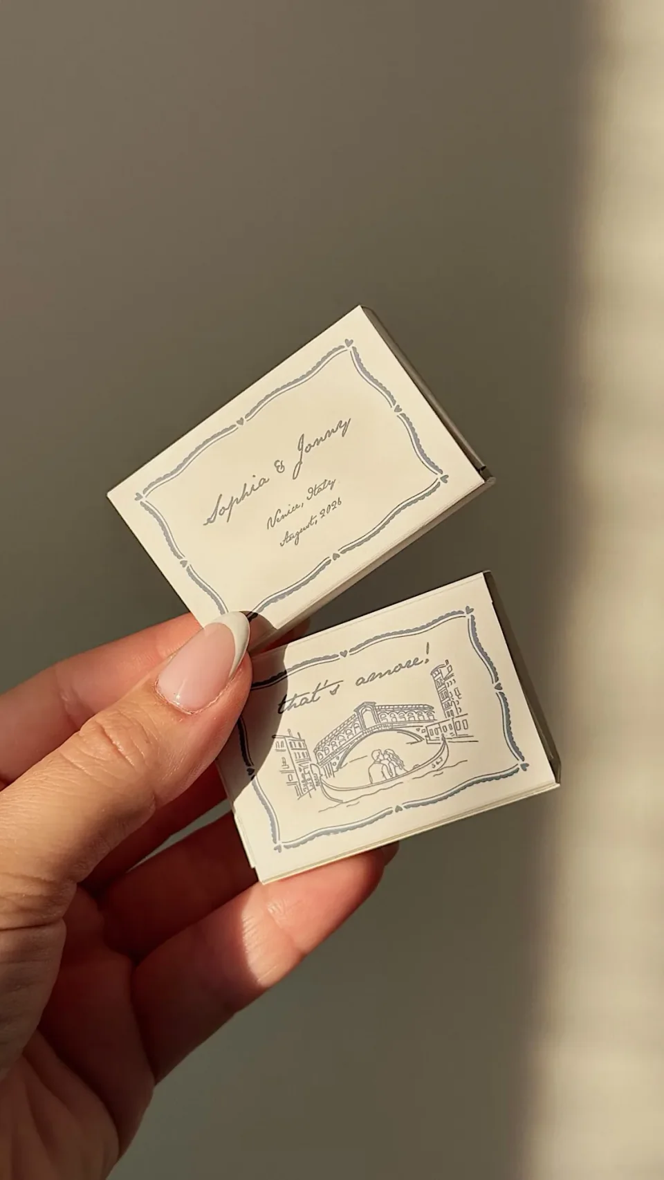 Ivory matchboxes in a blue ribbon frame with names and a gondola beneath a bridge